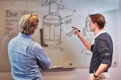 lifestyle photography of two men observing a sketch of a product on white board for Datum