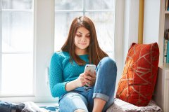 lifestyle photography of girl sitting by window bench on her phone for Jassby in Waltham, MA