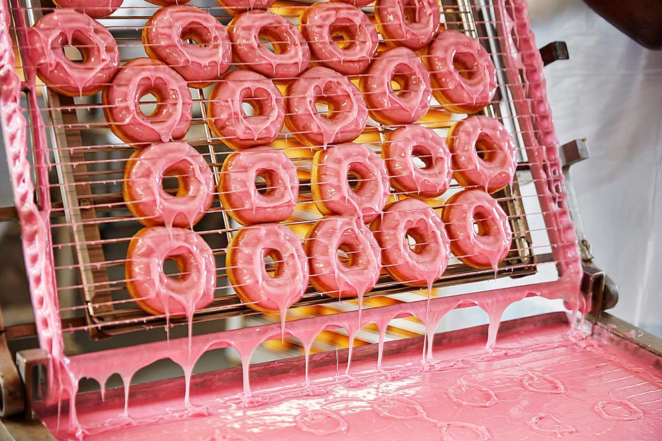 Food photography of Dunkin Donuts donuts being glazed at the Dunkin production facility. Food photography of Dunkin Donuts donuts being glazed at the Dunkin production facility.