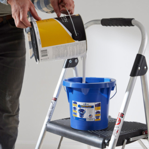 Lifestyle photography of a man pouring paint into United Solutions paint bucket for United Solutions in Leominster, MA Lifestyle photography of a man pouring paint into United Solutions paint bucket for United Solutions in Leominster, MA