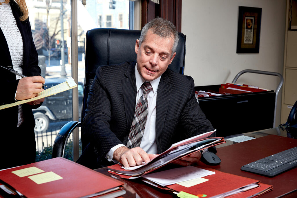 Lifestyle photography of Voccola Law lawyer sitting at a desk pointing to documents for Voccola Law in Providence, RI