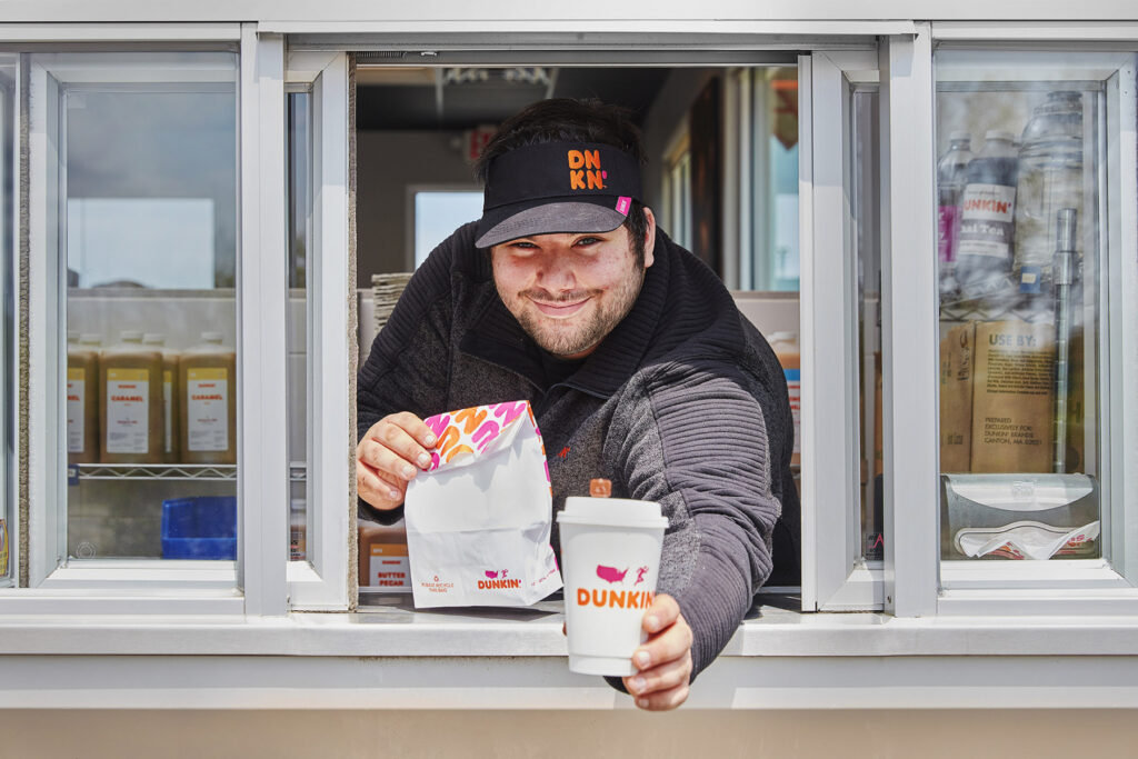 lifestyle photography of Dunkin drive thru worker handing food and a drink  for Dunkin Donuts