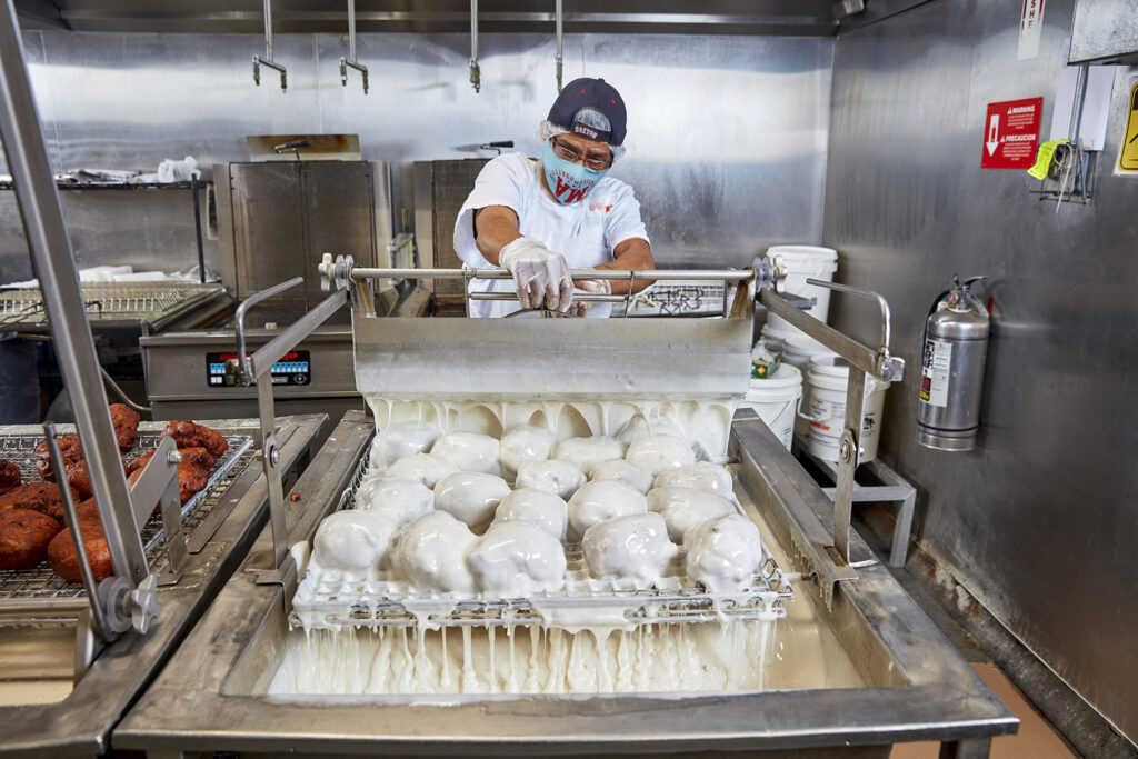 lifestyle photography of Dunkin worker glazing donuts for Dunkin Donuts