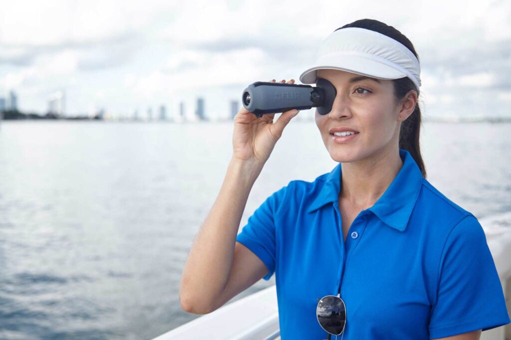 Lifestyle photography of a female holding Raymarine FLIR ScoutTK3 up to her eye for Teledyne-FLIR of Hudson, NH.