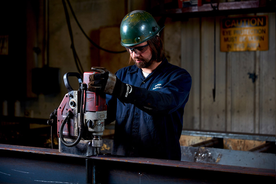Lifestyle photography of man with helmet using welding machine on metal for Package Steel of Sutton, MA.