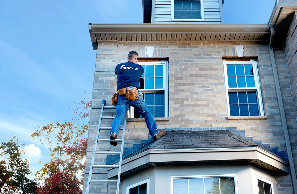 lifestyle photography of man on ladder installing window on house for Renoviso of Boston, MA.
