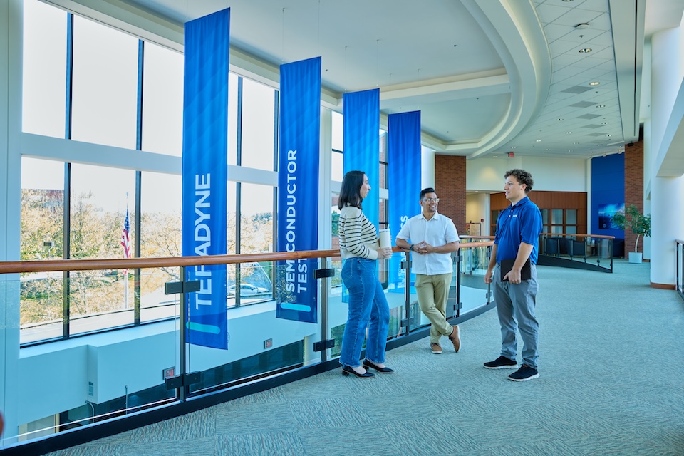 Lifestyle photography of three employees conversing in a hallway at Teradyne of North Reading, MA.