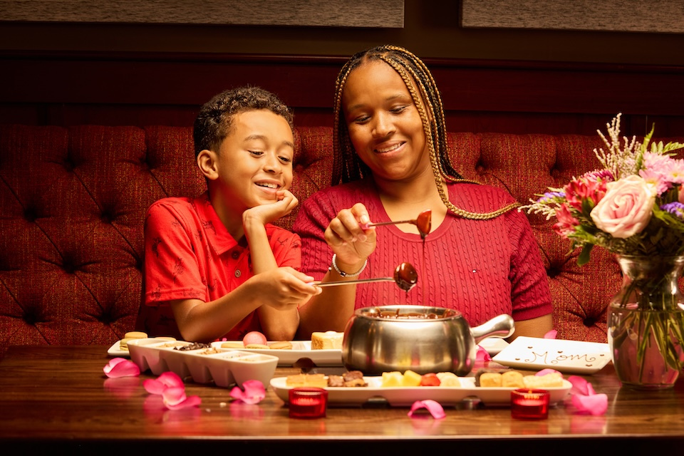 Lifestyle photography of woman and child in red eating fondue dessert together and smiling in Melting Pot of Bedford, MA