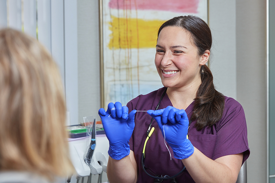 lifestyle photography of smiling dentist preparing floss for Nevins Dental Center of Boston, MA.