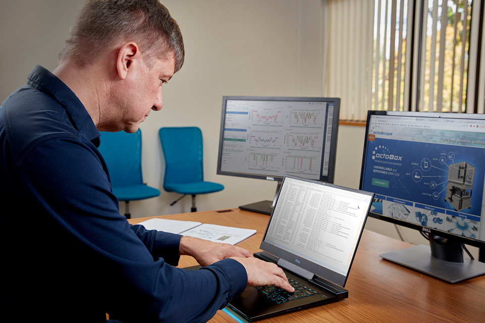 lifestyle photography of man sitting at desk in front of three monitors FieldPal for Octoscope of Littleton, MA.