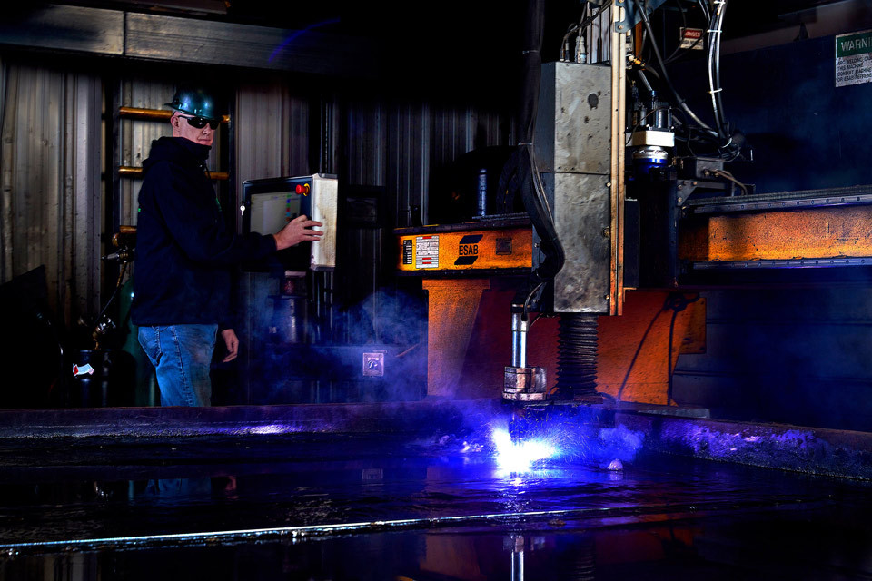 lifestyle photography of man operating a machine that is welding for Package Steel of Sutton, MA