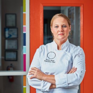 Portrait photography of Chef Sarah Wade with her arms crossed standing in front of her studio in Boston, MA Portrait photography of Chef Sarah Wade with her arms crossed standing in front of her studio in Boston, MA