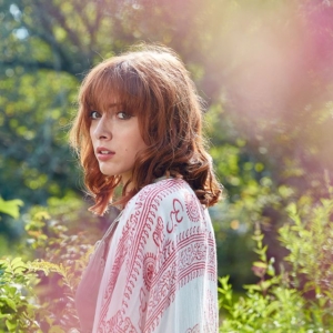 2G9A3501 portrait of woman standing near bushes and looking towards the camera over her shoulder