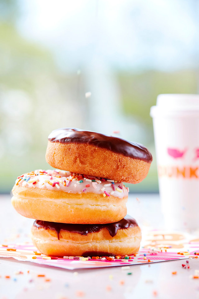 Product Photography of a stack of three Dunkin Donuts donuts with coffee in background