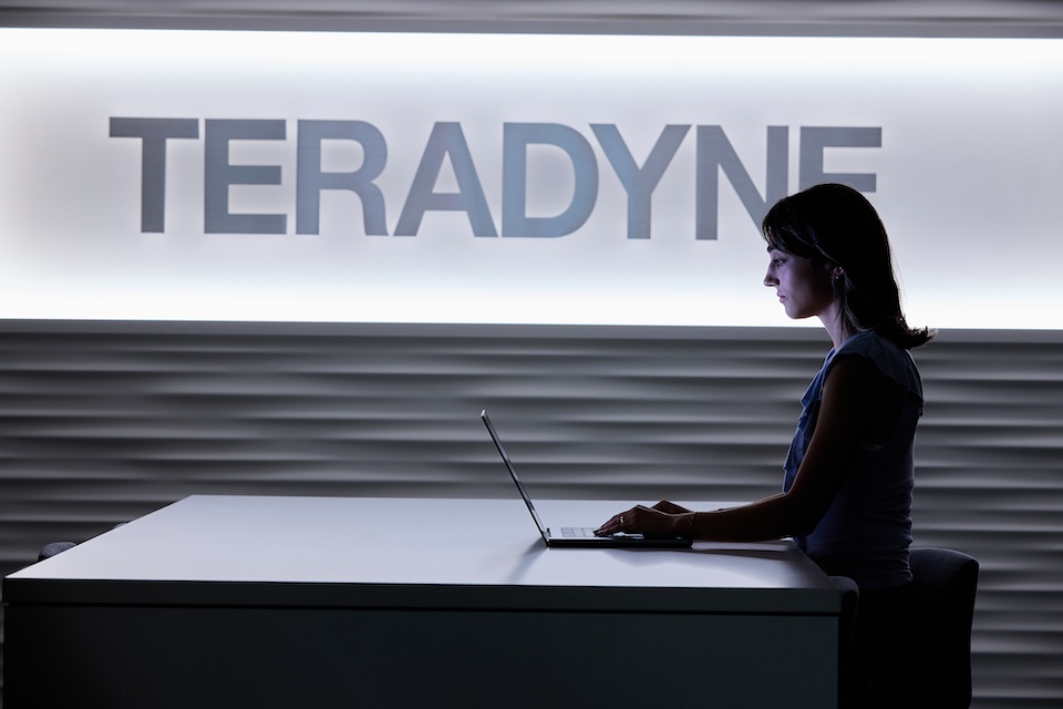 Lifestyle photography of a female employee seated at a table with a laptop at Teradyne of North Reading, MA.