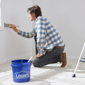 lifestyle photography of man painting walls with a Lowe's bucket in front of him for United Solutions in Leominster, MA