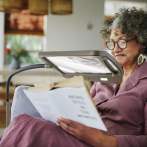 Lifestyle photography of a Mature woman reading a book while sitting on a sofa in her living room at home and in the afternoon for Daylight 24 in Andover, MA Lifestyle photography of a Mature woman reading a book while sitting on a sofa in her living room at home and in the afternoon for Daylight 24 in Andover, MA