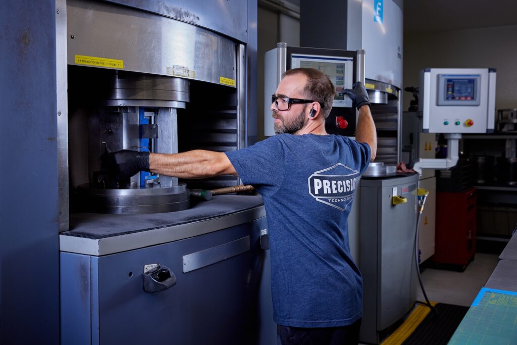 Worker operating machine in machine shop/industrial setting.